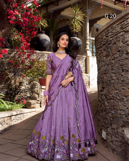 Woman in a purple embroidered saree standing outdoors with decorative elements.