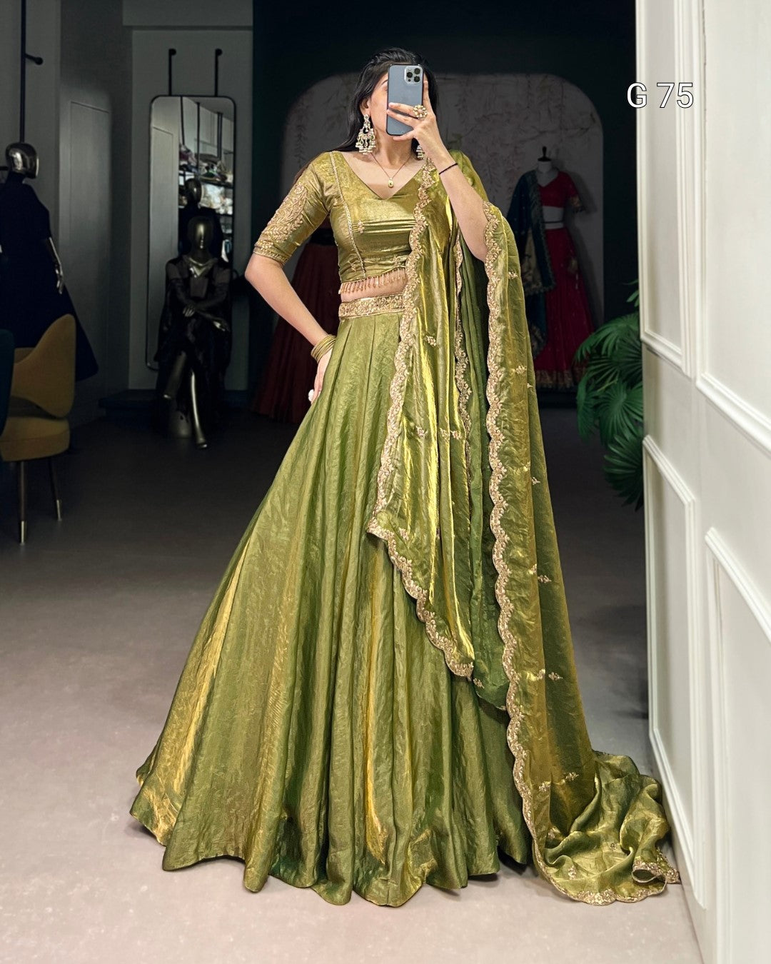 Woman wearing a green traditional outfit with a matching dupatta in a room.