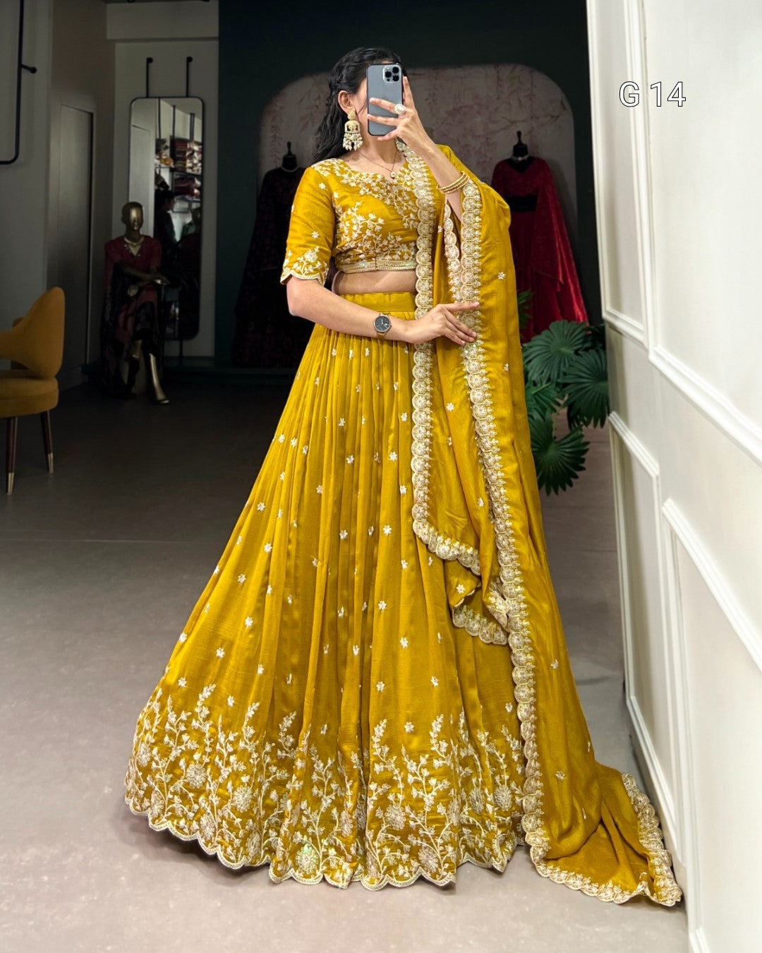 Woman in a yellow traditional outfit with floral patterns taking a mirror selfie.