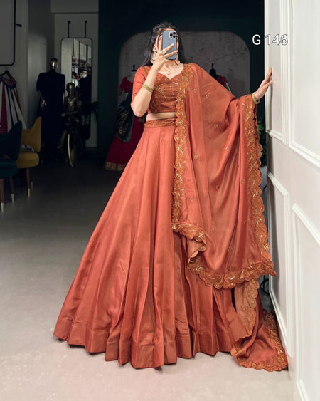 Person wearing a traditional orange outfit with intricate designs, standing in a room.