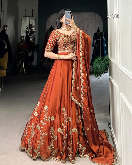 Woman in a traditional orange and gold embroidered outfit taking a mirror selfie.