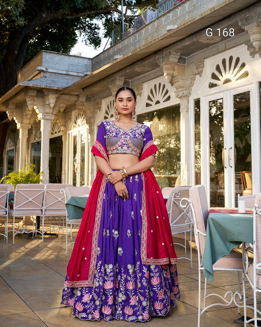 Woman in a traditional outfit standing outdoors with a building in the background