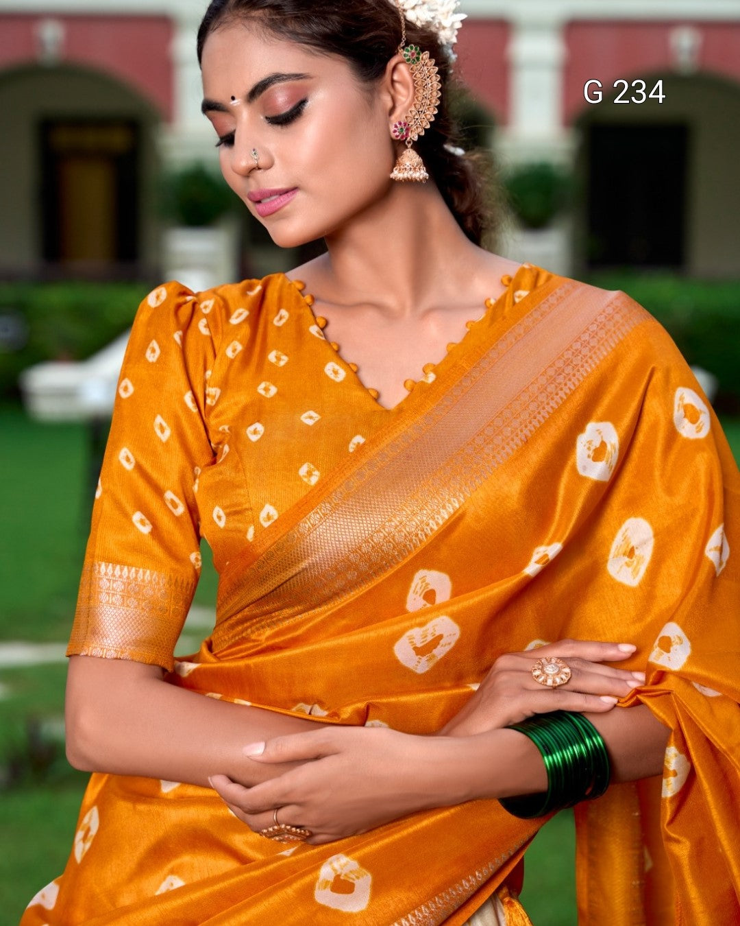 Woman wearing an orange saree with white patterns in an outdoor setting
