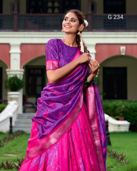 Woman in a pink and purple saree standing outdoors with a building in the background