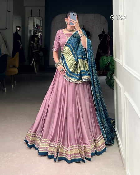 Person wearing a traditional pink and blue outfit with a matching dupatta in a room.