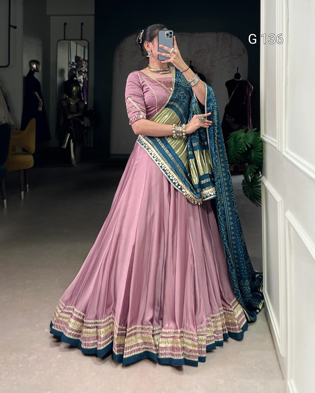 Woman in a pink saree with blue and gold border taking a mirror selfie.