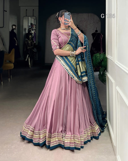 Woman in a pink saree with blue and gold border taking a mirror selfie.