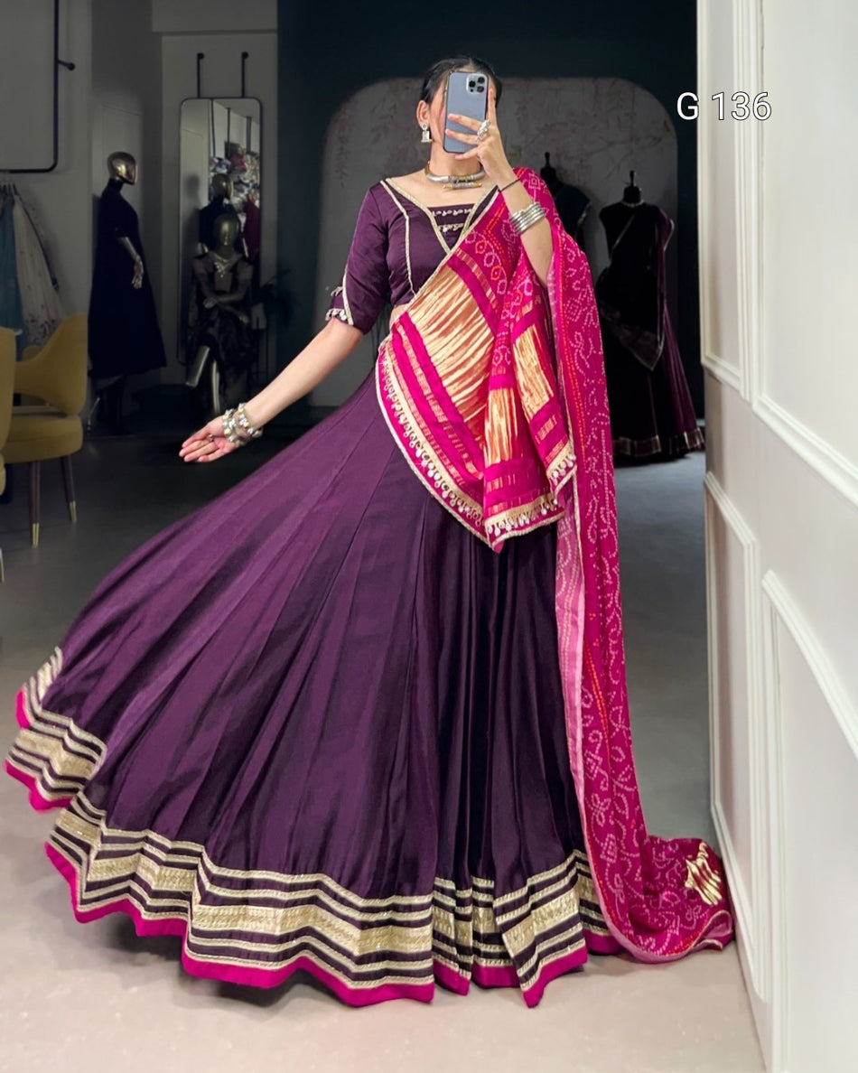 Person wearing a purple saree with pink blouse in a room setting