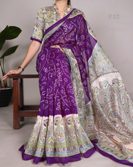 Woman wearing a purple and white patterned saree with a matching blouse, sitting on a wooden stool.