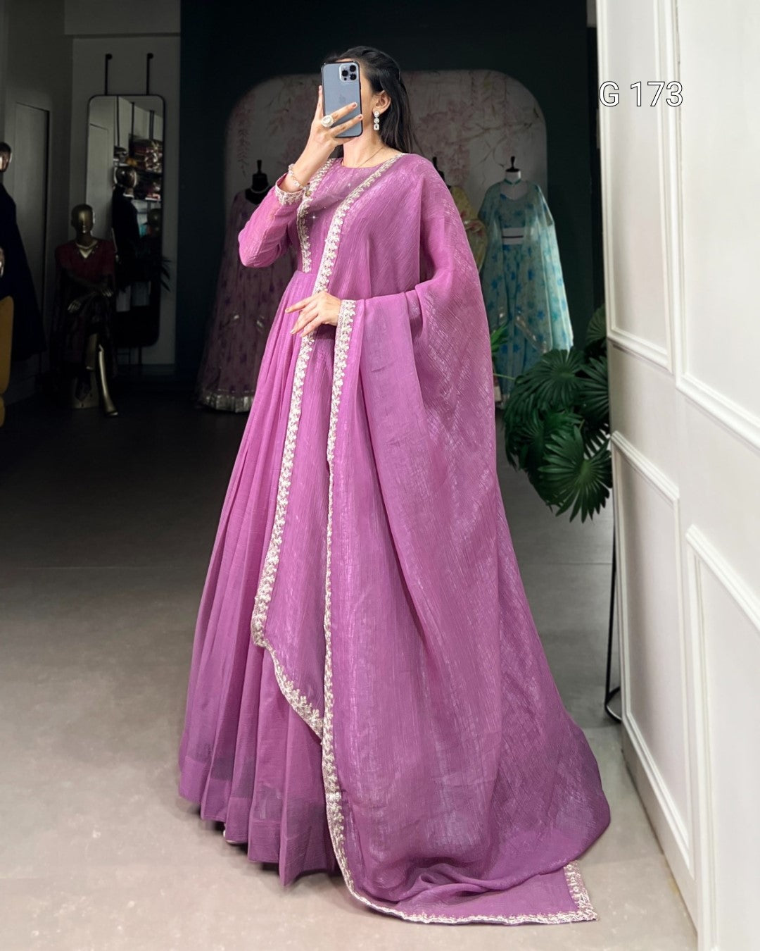 Woman wearing a pink saree with a white border in a room setting.