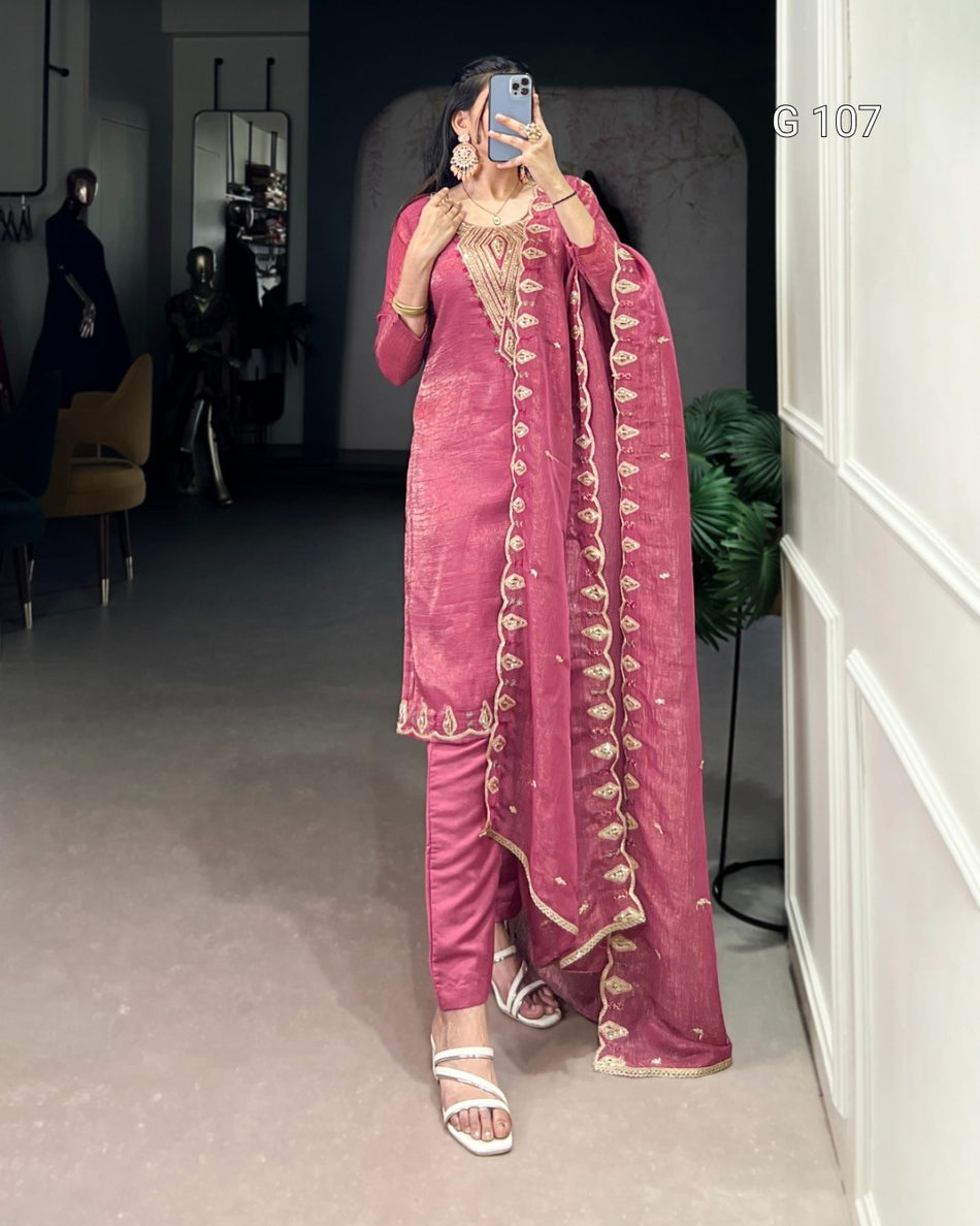 Person wearing a pink traditional outfit with gold embroidery in a room.