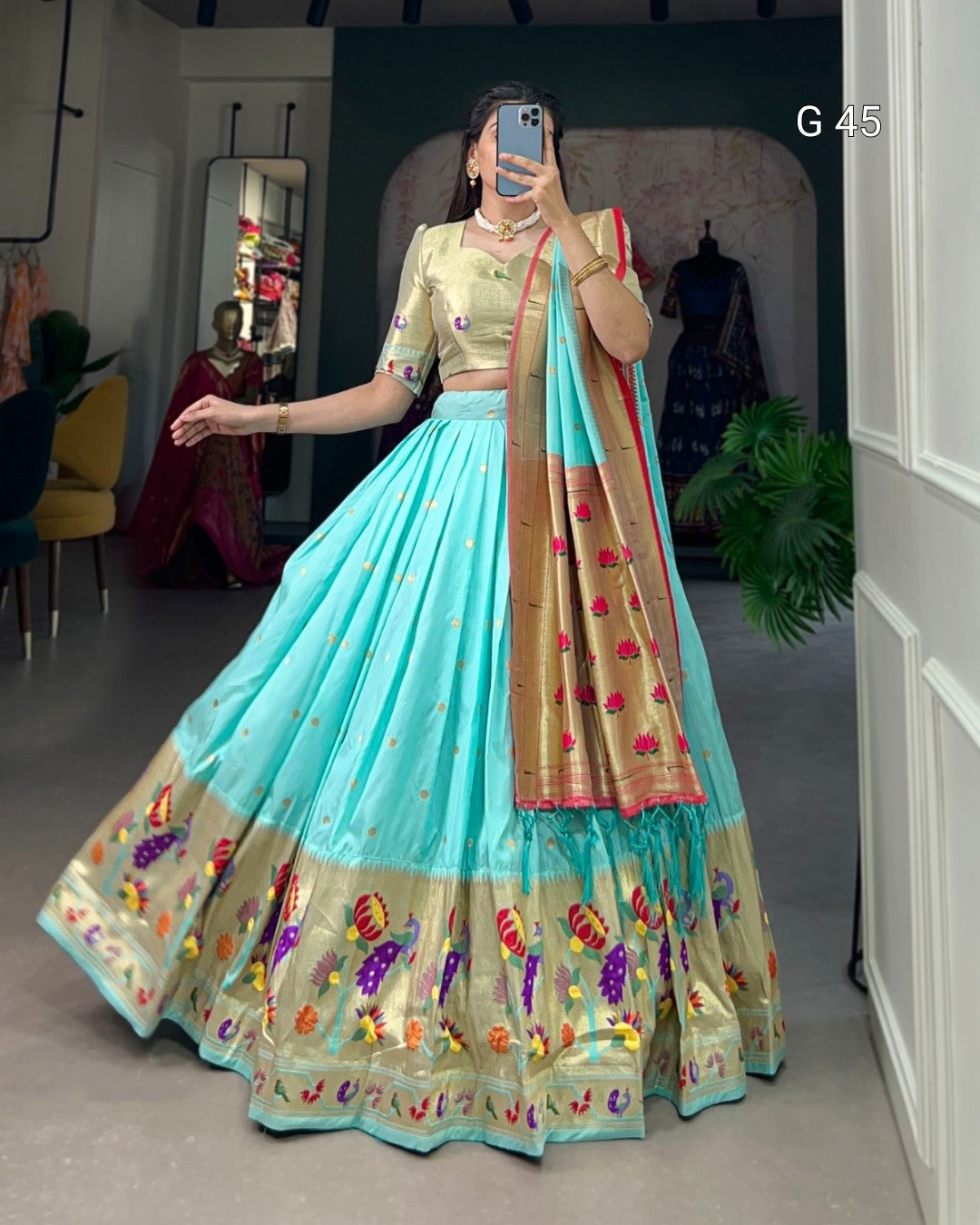 Woman wearing a traditional outfit with a blue and gold saree in a room.