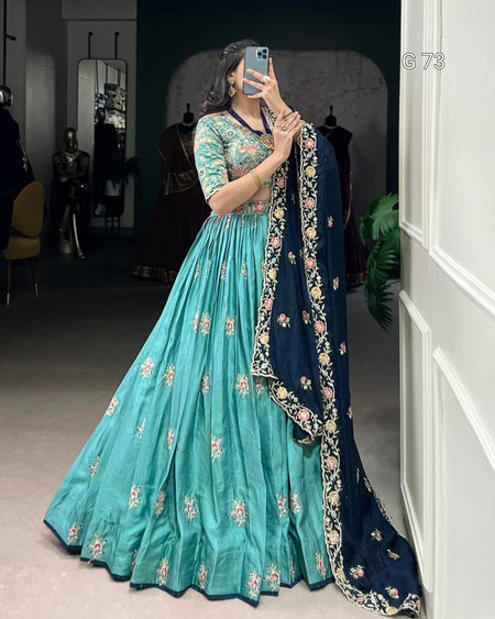 Woman in a teal and navy embroidered traditional outfit taking a mirror selfie.