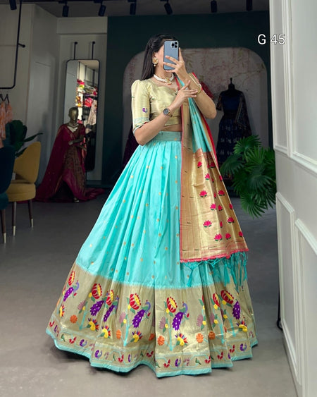 Woman wearing a traditional outfit with a blue and gold sari in a room.
