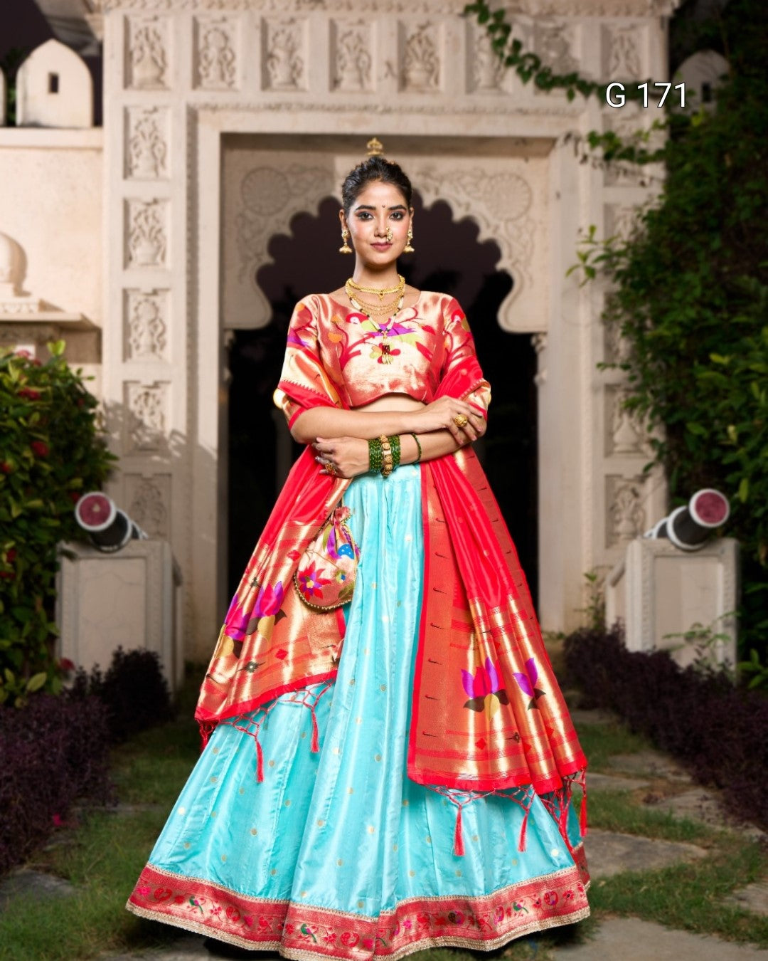 Woman in a traditional outfit with a red and blue design standing in front of an ornate white door.
