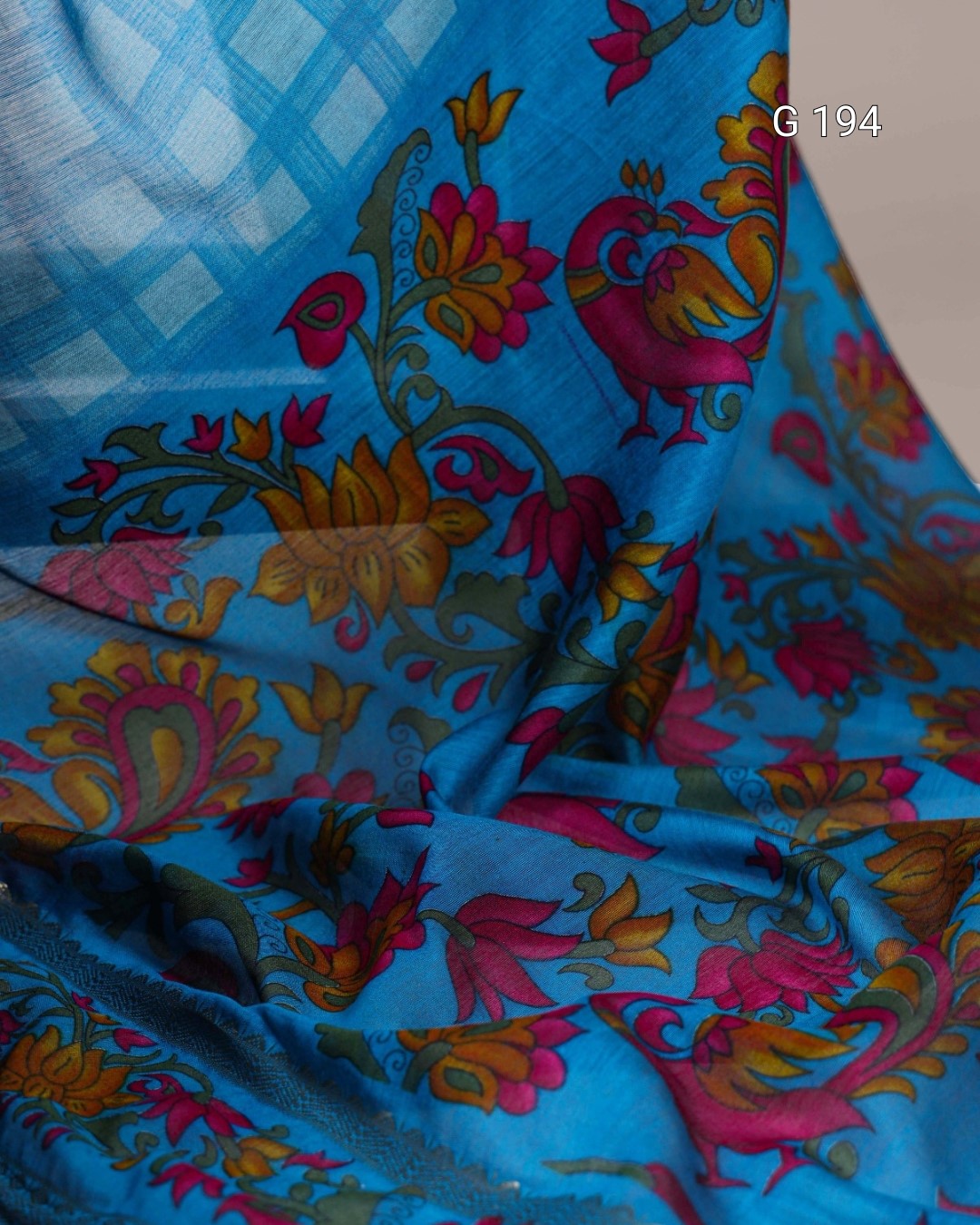 Colorful floral and peacock pattern on a blue fabric background