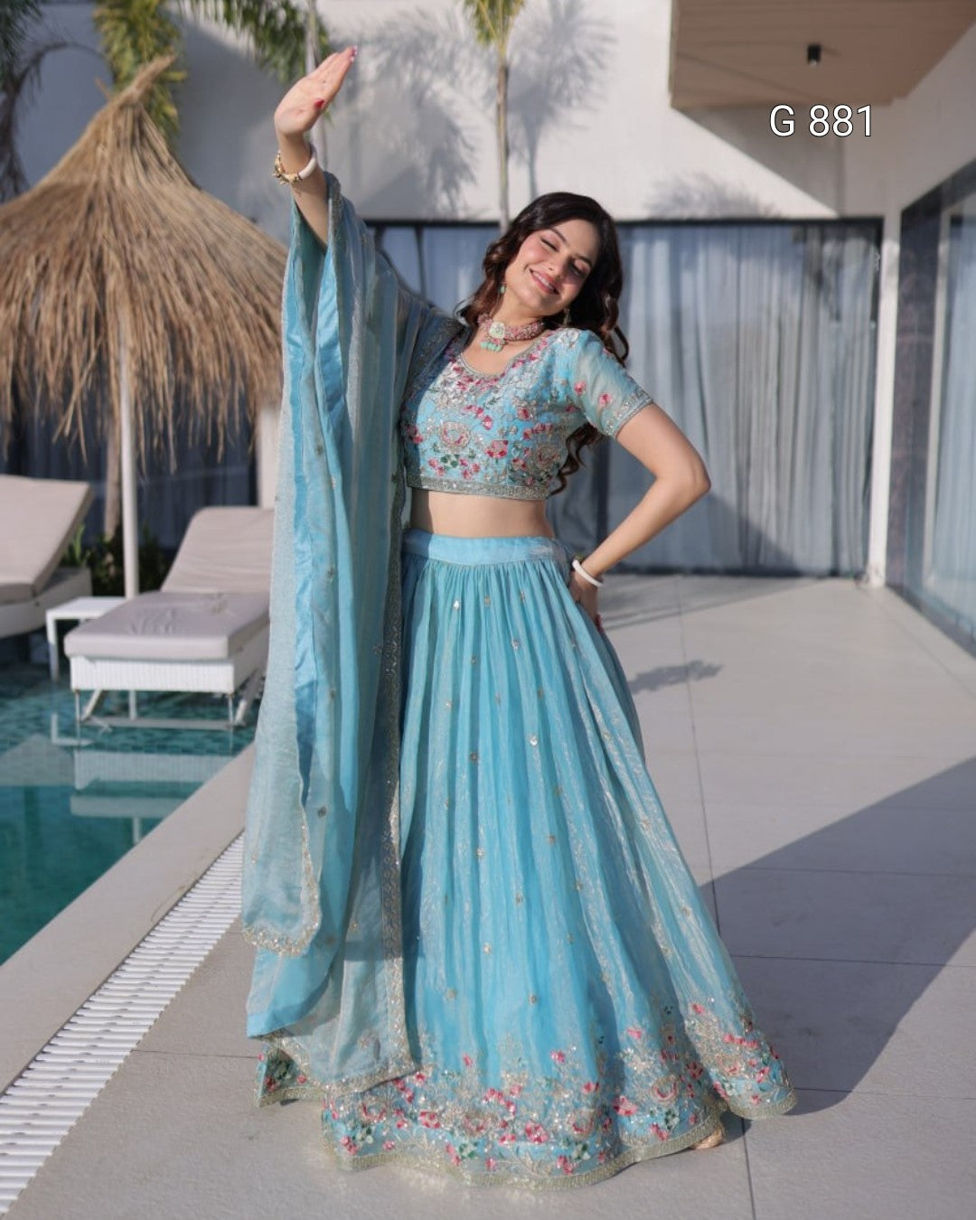 Woman in a light blue traditional outfit standing by a poolside.