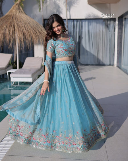 Woman in a blue embroidered traditional outfit standing by a poolside.
