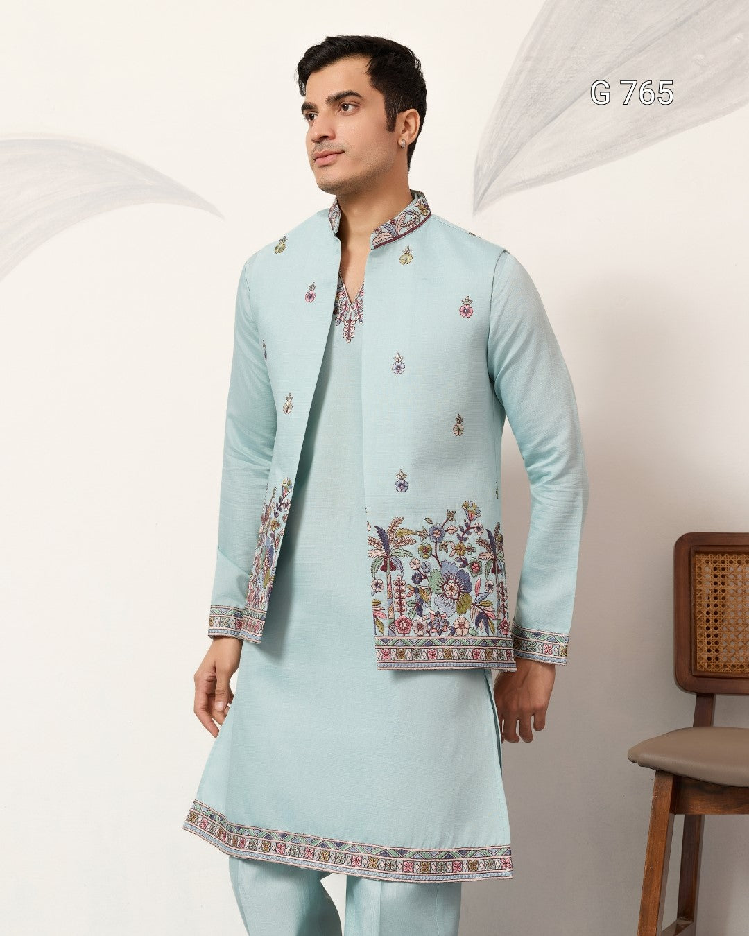 Man wearing a light blue embroidered traditional outfit against a white background