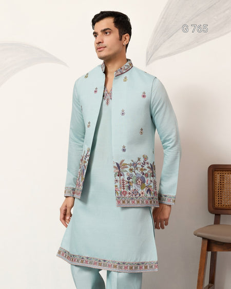 Man wearing a light blue embroidered traditional outfit against a white background
