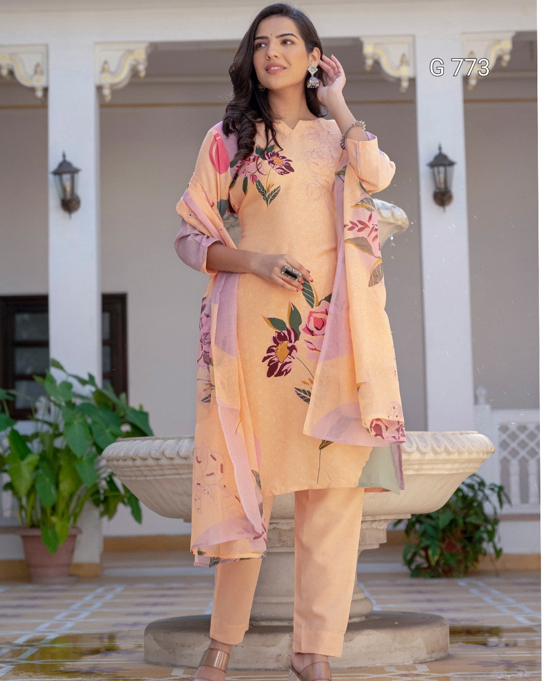 Woman in peach floral outfit standing in a decorative outdoor setting
