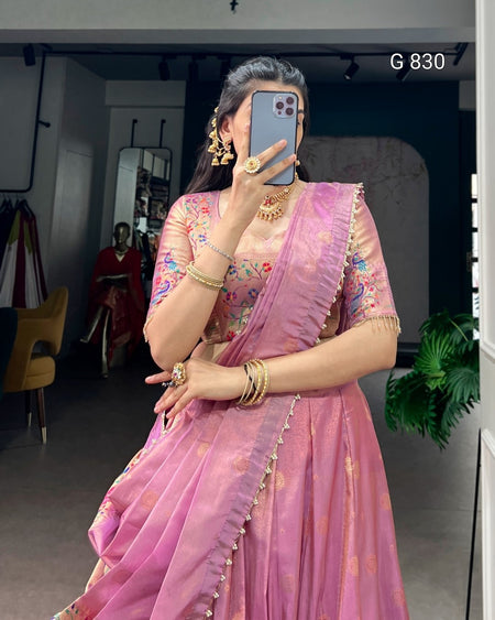 Woman in a pink saree with gold details taking a mirror selfie.