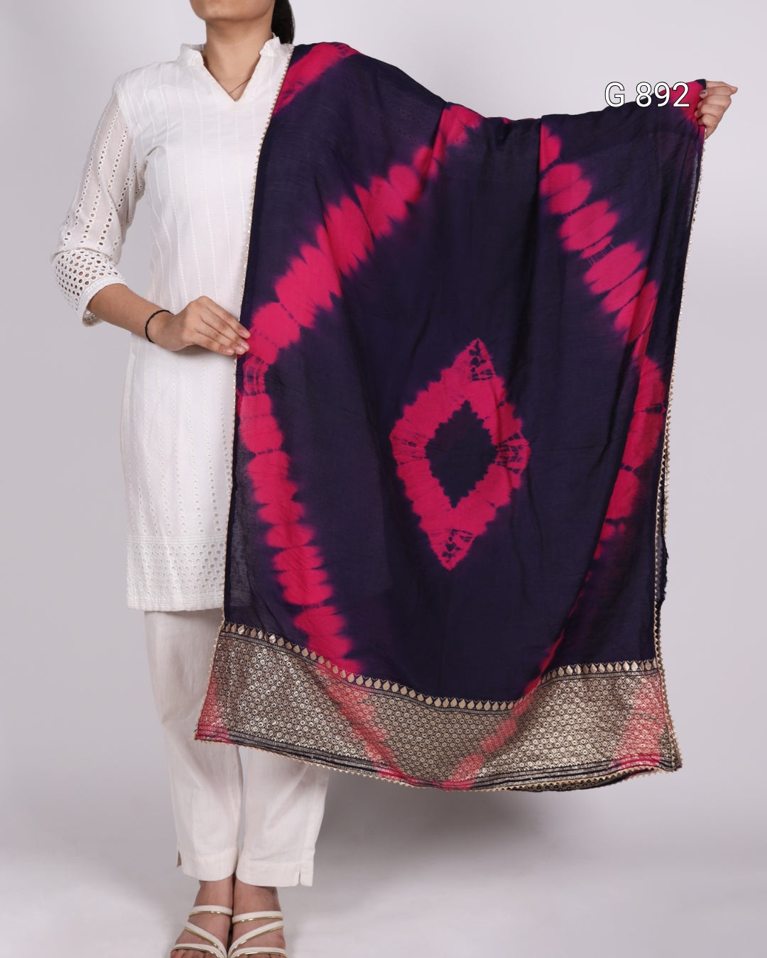 Person holding a dark blue and pink patterned scarf against a white background