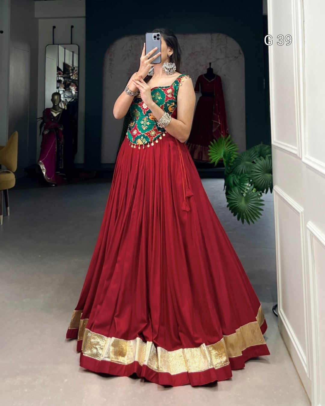 Person wearing a traditional red and green outfit with gold details, standing in a room.