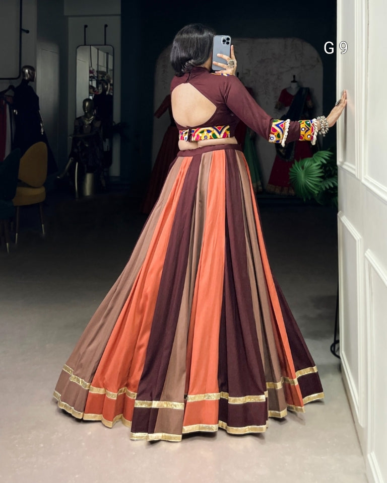 Woman in a colorful dress standing in a room with mirrors.