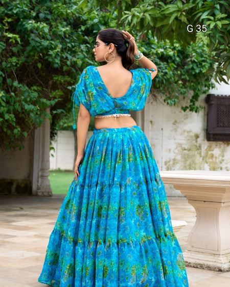 Woman wearing a blue floral dress standing outdoors with greenery in the background