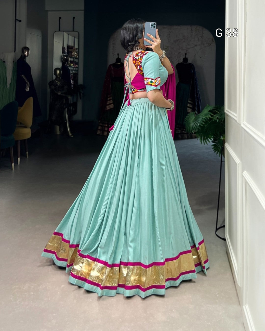 Person wearing a light blue saree with gold border in a room setting.