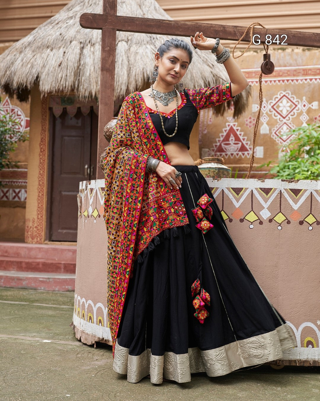 Woman in traditional black and red outfit with floral details against a decorative background