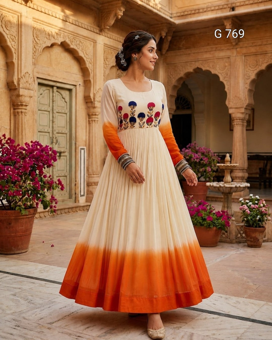 Woman in a white and orange dress with floral patterns standing in an ornate courtyard.