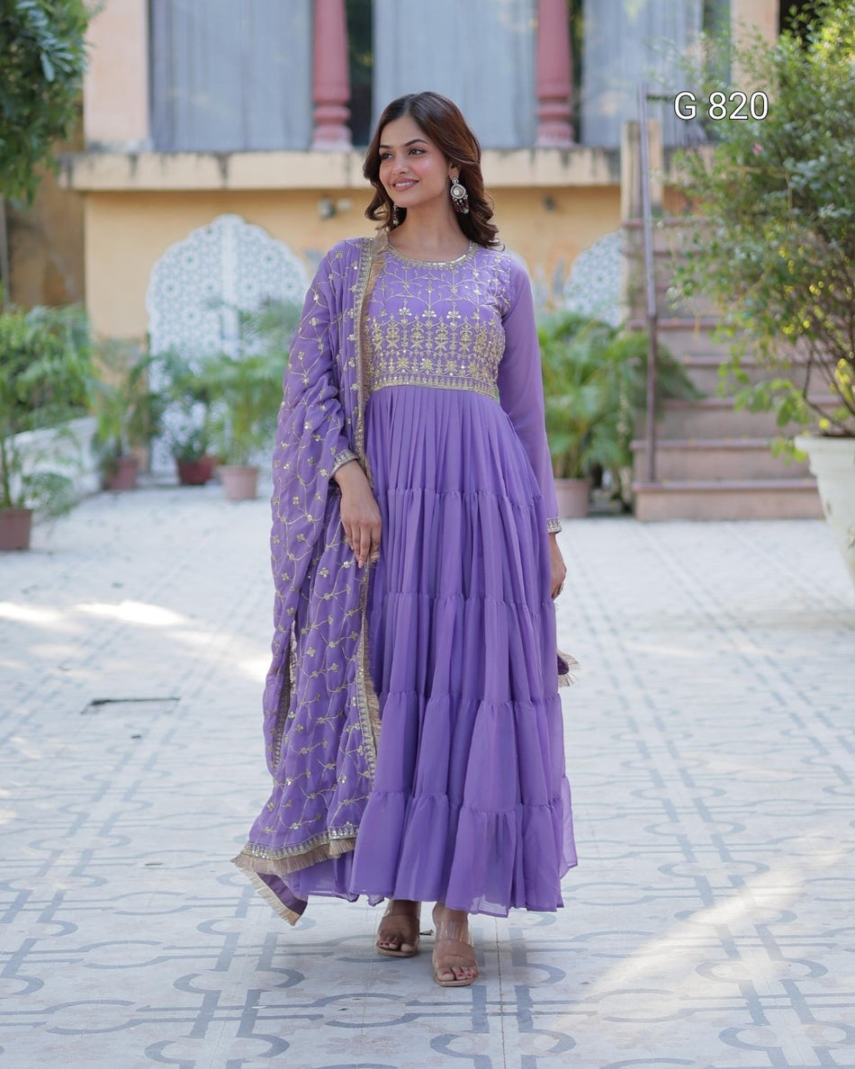 Woman wearing a purple traditional outfit with gold details outdoors.