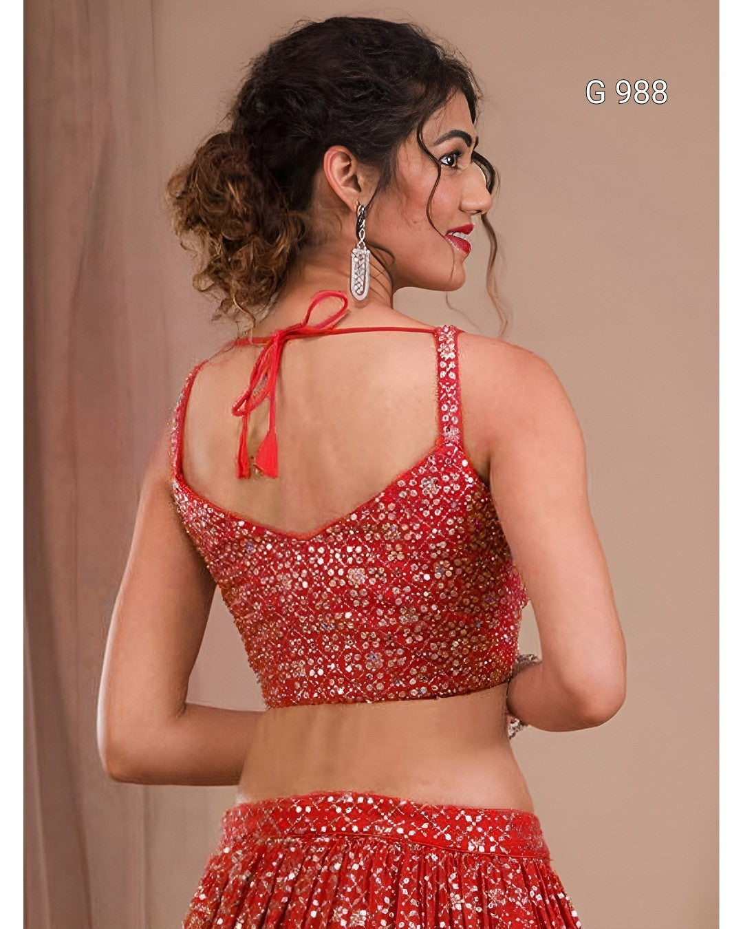 A woman shown from the back wearing a red embellished crop top and matching skirt, with a beige studio background and the text 'G 988' in the top right.