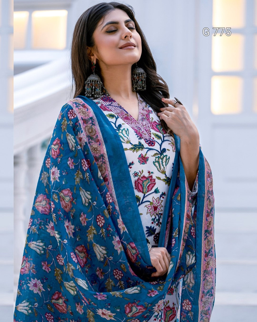 Woman wearing a floral dress with a blue dupatta in an indoor setting
