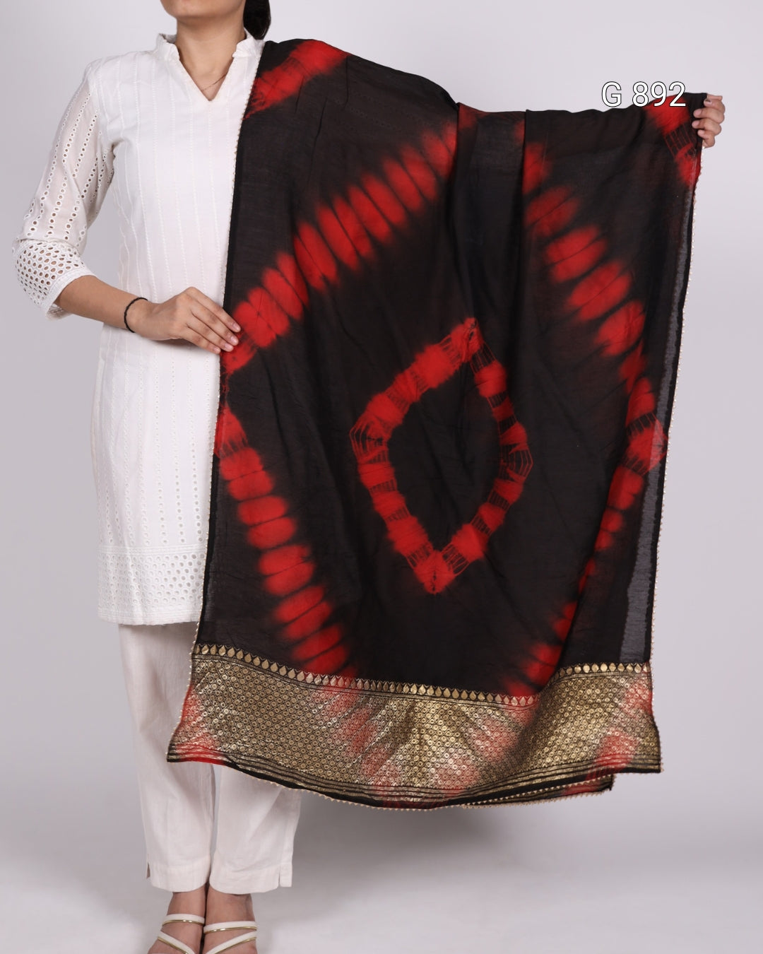 Person holding a black and red patterned scarf with a white background