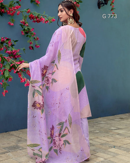 Woman wearing a floral purple saree with a blue wall and pink flowers in the background