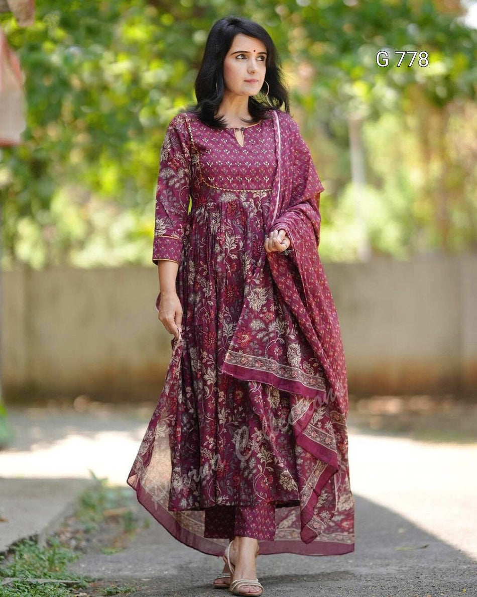 Woman wearing a maroon patterned dress with a dupatta outdoors