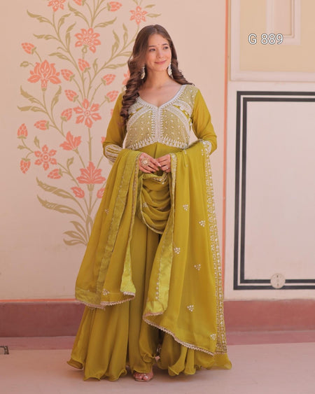 Woman in a green traditional outfit with floral patterns on a decorated wall.