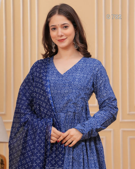 Woman wearing a blue patterned dress against a beige wall.