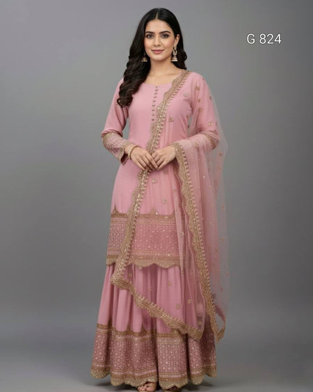 Woman wearing a pink traditional outfit with gold embroidery on a gray background