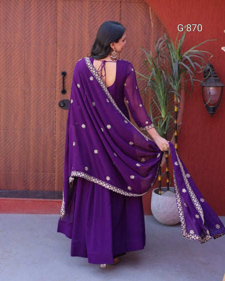 Woman wearing a purple traditional outfit with a red wall and plant in the background