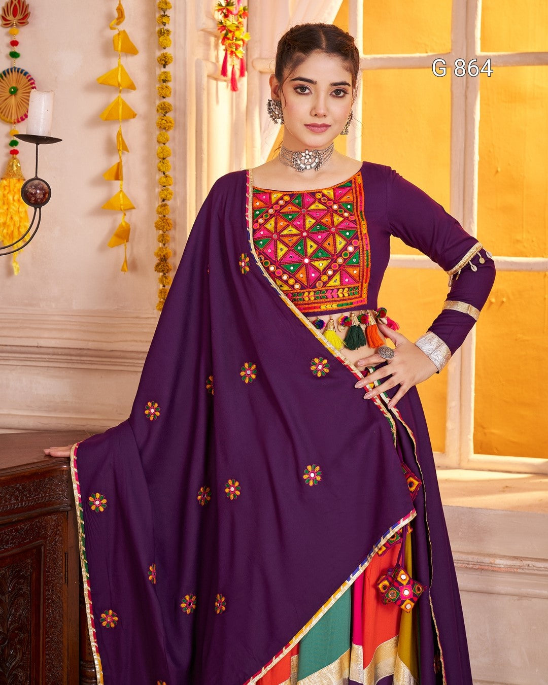 Woman wearing a traditional outfit with colorful embroidery in a decorated room.