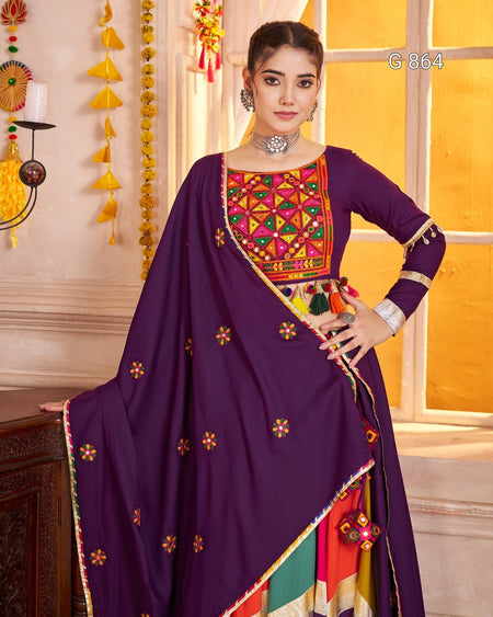 Woman wearing a traditional outfit with colorful embroidery in a decorated room.