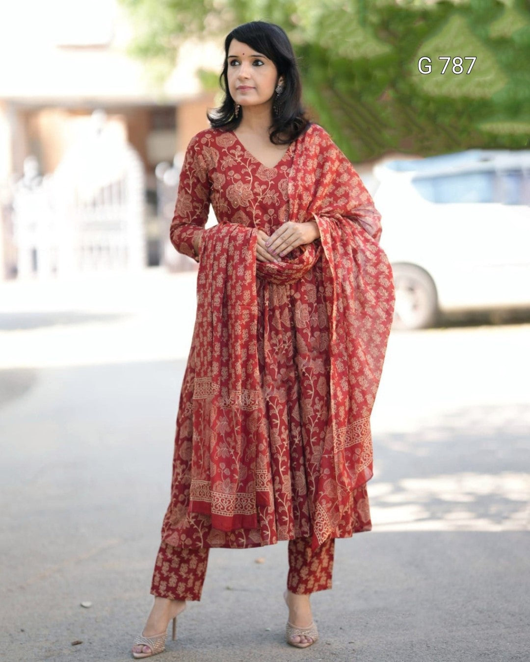 Woman wearing a red patterned outfit standing outdoors with blurred background