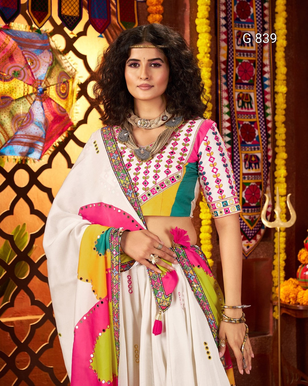 Woman in a colorful traditional outfit with intricate patterns against a decorative background