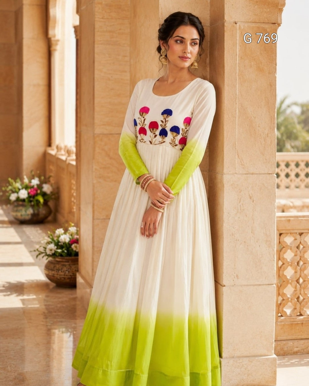 Woman wearing a white and green dress with floral embroidery in an outdoor setting.