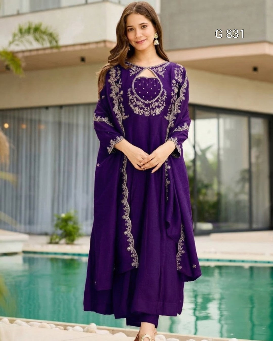 Woman wearing a purple dress with white embroidery by a poolside.