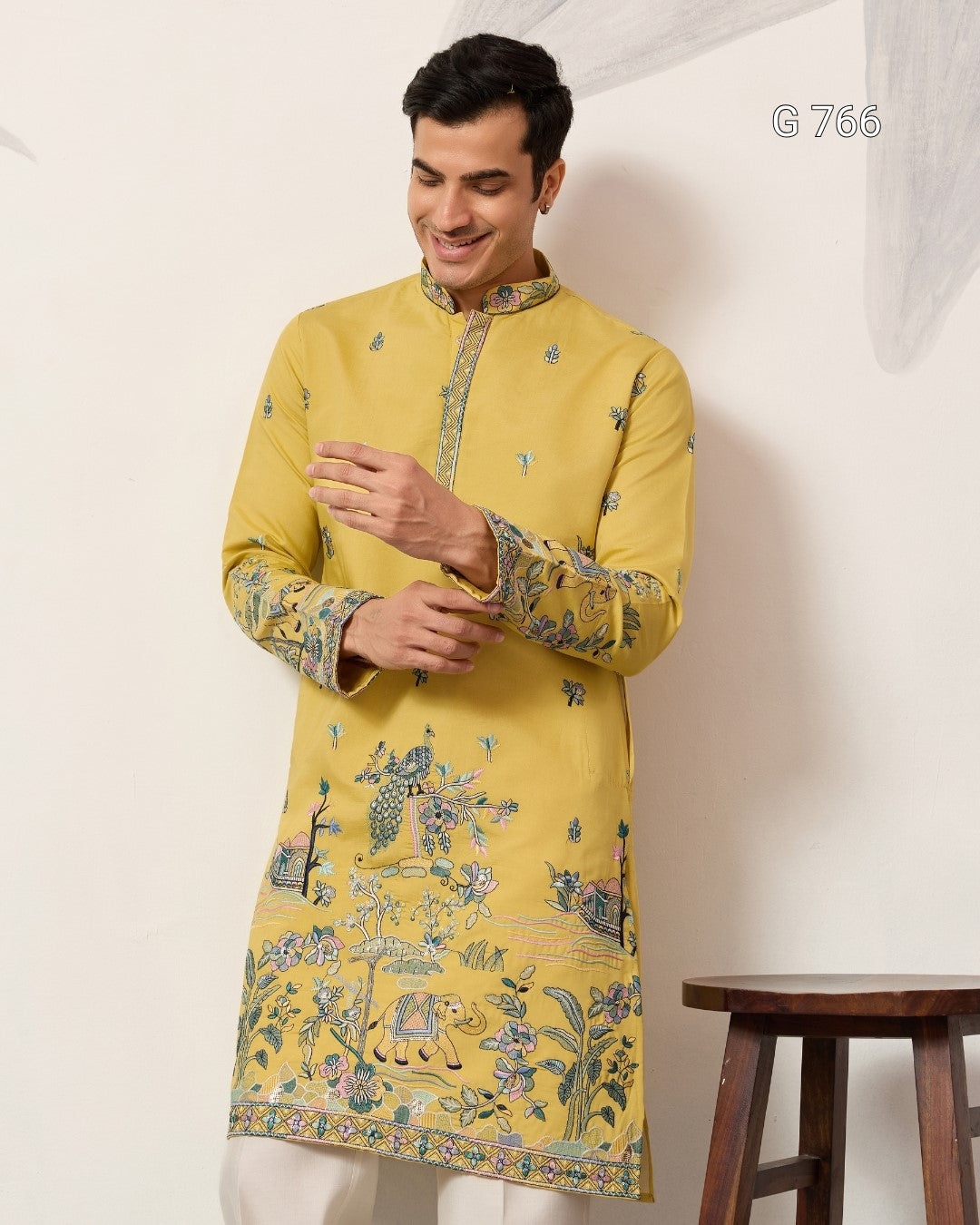 Man wearing a yellow kurta with intricate patterns against a white background